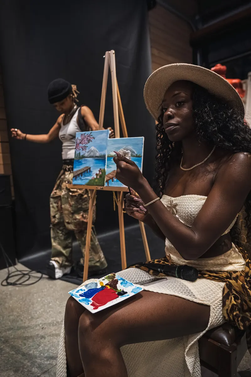 A guest painting at an easel while the artist works beside her at 1712 Studios