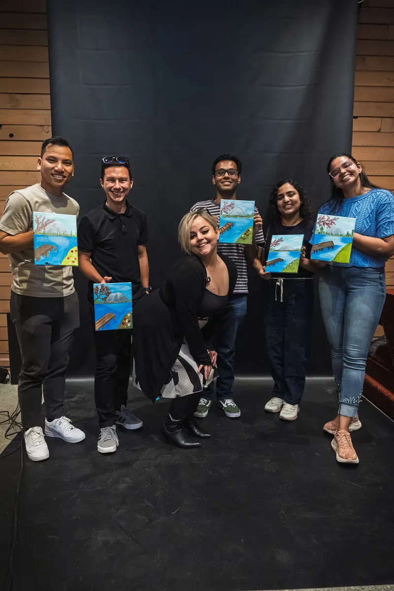 Six guests holding up their finished paintings