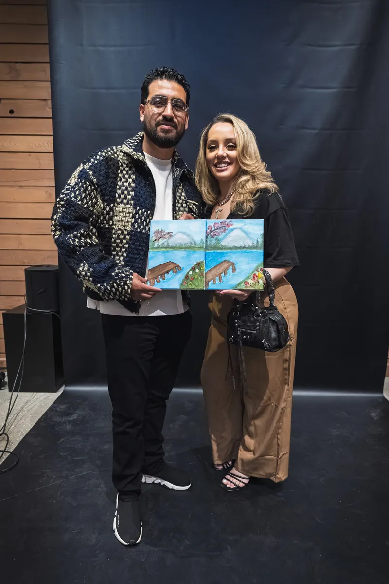 Two guests posing with their paintings