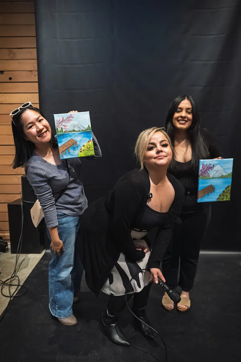 Three guests laughing and showing their paintings
